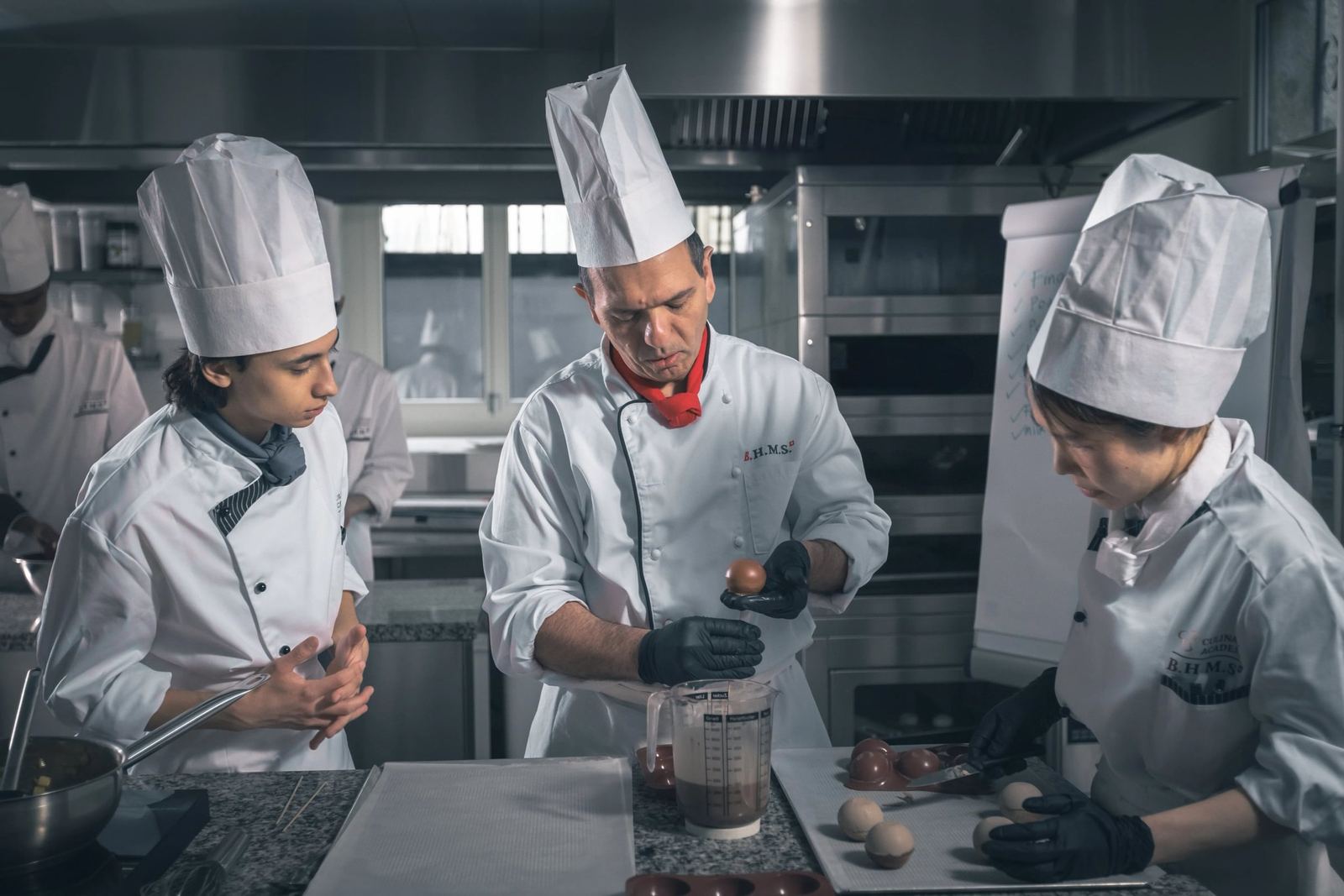 A chef instructor demonstrates chocolate work to BHMS students in the Lucerne chocolate lab