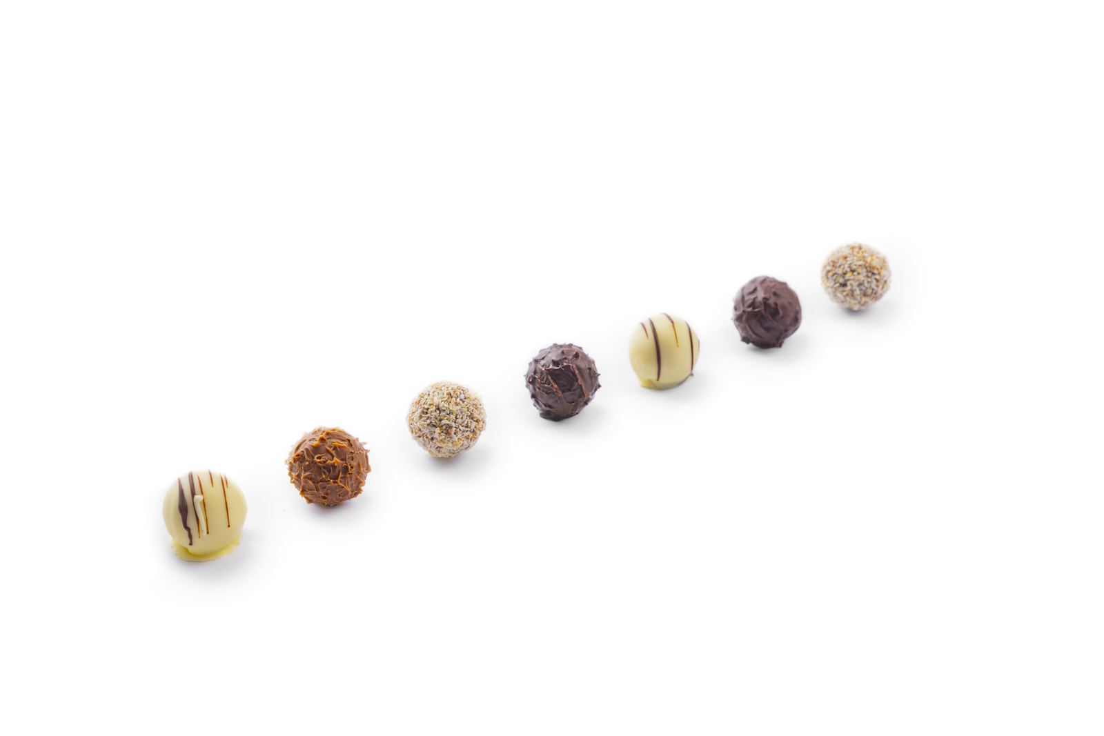 Seven chocolate truffles in white, milk, dark and nut coatings arranged diagonally